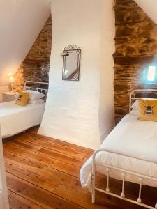 a bedroom with two beds and a stone wall at Trevejean chambre d'hotes de charme in Guerlédan