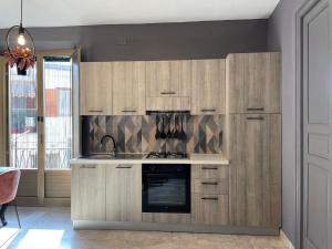 a kitchen with wooden cabinets and a stove top oven at Il Monocolo - Affitti Brevi in Racalmuto