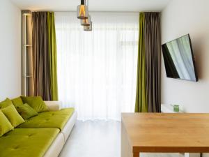 a living room with a green couch and a table at Nature Loft by the river in Buşteni