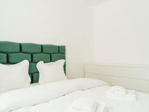 a bed with white pillows and a green headboard at Nature Loft by the river in Buşteni