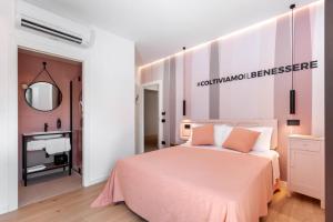 1 dormitorio con cama rosa y espejo en La Sentina Experience en San Benedetto del Tronto