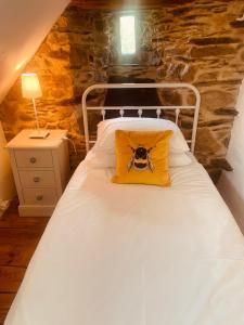 Una cama con una almohada amarilla con una cámara. en Trevejean chambre d'hotes de charme, en Guerlédan