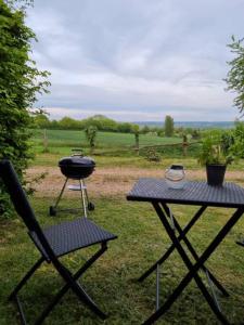 una griglia e una sedia accanto a un tavolo da picnic di Gite de la Piegerie a Courgenard