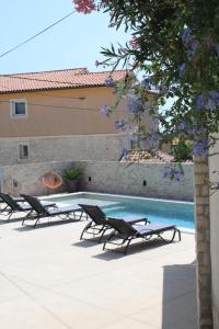 利兹扬Apartments Mia with pool near Medulin的一座带躺椅的游泳池位于大楼旁