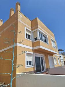 a building with a tree in front of it at Apartamentos La Calilla Cabo de Gata in El Cabo de Gata