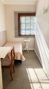 a room with a bed and a table and a window at Moradia Compartilhada Pelotas in Pelotas
