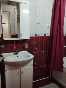 a bathroom with a sink and a red shower curtain at Dana in Trnava