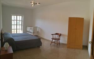1 dormitorio con 1 cama, armario de madera y silla en Le Palme di Riace 2, en Riace Marina