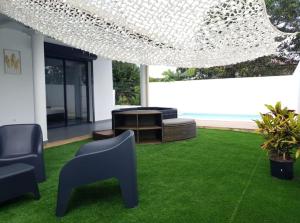 una sala de estar con un patio verde con sillas en La Palmeraie Lodge Terrasse & Piscine et Jacuzzi, en Matoury