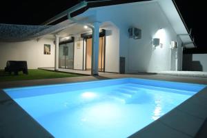 a swimming pool lit up at night in a house at La Palmeraie Lodge Terrasse & Piscine et Jacuzzi in Matoury
