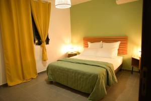 - une chambre avec un lit et des rideaux jaunes dans l'établissement La Palmeraie Lodge Terrasse & Piscine et Jacuzzi, à Matoury