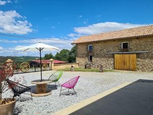 a patio with chairs and a table and an umbrella at Corps de Ferme Labarthe à Pimbo in Pimbo