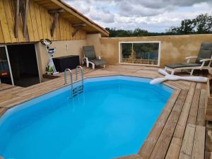 a swimming pool with a wooden deck and a swimming poolvisor at Corps de Ferme Labarthe à Pimbo in Pimbo