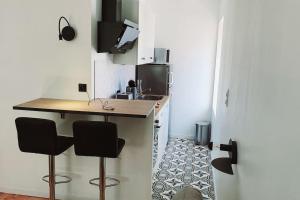 uma cozinha com um balcão e dois bancos de bar em Charmant studio en centre-ville em Saint-Dié-des-Vosges