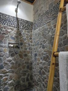 y baño con ducha de piedra y pared de piedra. en Villa Ilo Komba en Nosy Komba