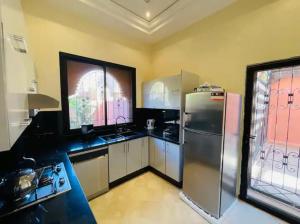 cocina con nevera de acero inoxidable y ventana en The Villa avec piscine 4 chambres, en Marrakech