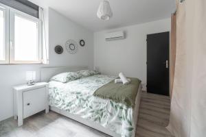 a white bedroom with a bed and a window at Résidence Le Celest - Appartements climatisés - Centre ville in Vichy