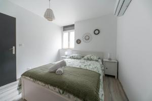 a white bedroom with a bed with towels on it at Résidence Le Celest - Appartements climatisés - Centre ville in Vichy +95 photos