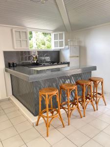 a kitchen with four bar stools and a counter at STUDIO VUE ROCHER DU DIAMANT in Le Marin