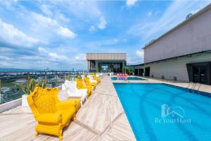a pool on the roof of a building with yellow chairs at Dorsett Residences Sri Hartamas (Kuala Lumpur) in Kuala Lumpur