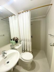 Baño blanco con aseo y lavamanos en Marshall’s Place Azure Staycation, en Manila
