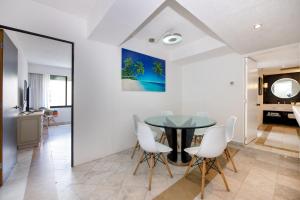 ein Esszimmer mit einem Glastisch und weißen Stühlen in der Unterkunft State of the Art Condos en la mejor Playa de Cancun frente a PLAZA LA ISLA in Cancún