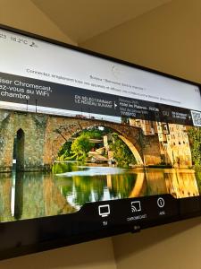 a television screen with a picture of a bridge at Hôtel les Platanes in Villeneuve-sur-Lot