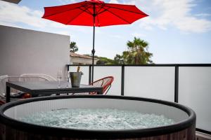 - une table avec un parasol rouge sur le balcon dans l'établissement Porticcio Vacations - Terrasse, Piscine, Jacuzzi, Vue Mer, Clim - by TGB, à Porticcio