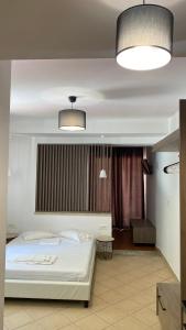 1 Schlafzimmer mit einem weißen Bett und 2 Leuchten in der Unterkunft Emerald Suites in Vryses