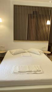 een wit bed met een handdoek erop bij Emerald Suites in Vryses