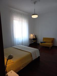 a bedroom with a bed and a chair and a window at Giulia Town House tra città e mare in Salerno