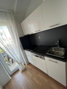 kuchnia z białymi szafkami, zlewem i oknem w obiekcie Ferienhaus Magdalena w Fažanie