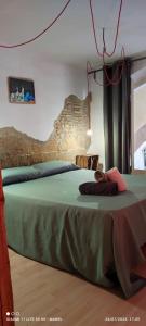 a bedroom with a green bed with a stone wall at La Impronta Relax in Lleida