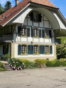 una casa con persianas azules y flores delante de ella en B&B tannen124 en Oberburg