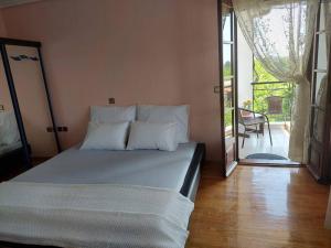 Schlafzimmer mit einem Bett und einer Tür zu einer Terrasse in der Unterkunft Olympos Philoxenia, μεταξύ βουνού και θάλασσας in Kateríni