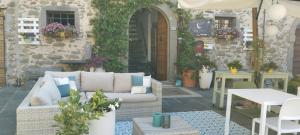 a patio with a couch and tables and an umbrella at B&B Luna & Stelle in Villafranca in Lunigiana