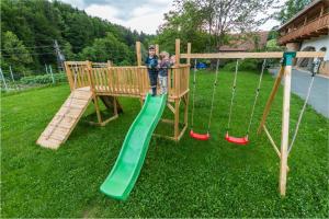 two children are standing in a wooden playground at Gästehaus Biohof Leutschach in Leutschach