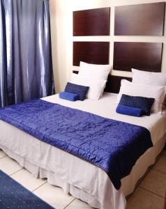 a bedroom with a large bed with blue pillows at Baobab Tree Guest House in Huntley