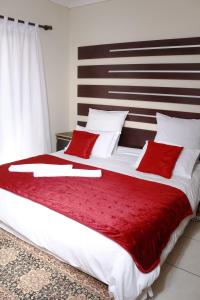 a bedroom with a large bed with red pillows at Baobab Tree Guest House in Huntley