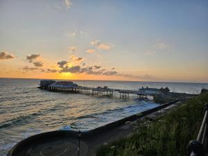 a pier in the ocean with the sun setting at Charming 1-Bed Apartment in Cromer Town Centre in Cromer