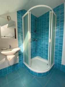 uma casa de banho em azulejos azuis com um chuveiro e um lavatório. em Chata Jahodná em Košice