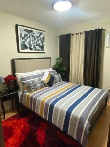 a bedroom with a bed with a striped comforter at Affordable 2 bedroom condo unit in Cagayan de Oro