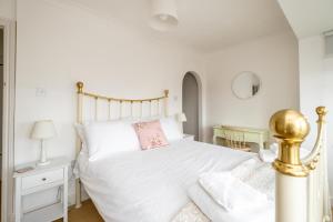 a bedroom with a white bed with a pink pillow at 69 Saxmundham Road in Aldeburgh