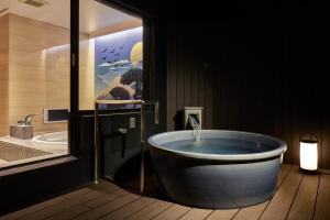 un bagno con una grande vasca in una stanza di Nagoya Hotel HOQA Hanaironoyu a Nagoya
