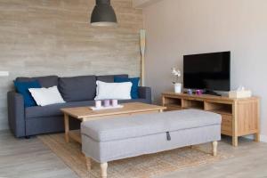 sala de estar con sofá azul y TV en Lloret de Mar - BeachSide Apartment - Free Parking en Lloret de Mar