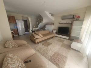 ein Wohnzimmer mit einem Sofa und einem TV in der Unterkunft CARETTA VİLLA in Antalya
