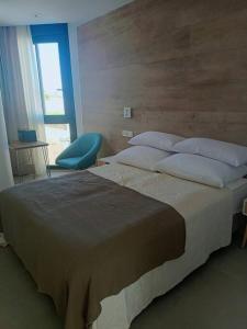 um quarto com uma cama grande e uma cadeira azul em Apartamento Santiago de La Ribera em Santiago de la Ribera
