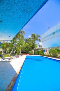 ein blauer Pool mit Stühlen und Palmen in der Unterkunft Hotel Caribe Internacional Cancun in Cancún