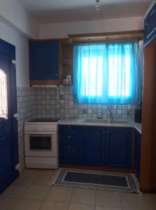 阿波羅的住宿－Apollon Sunrise，厨房配有蓝色橱柜、水槽和窗户。