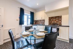 cocina con mesa de cristal y sillas negras en Chesterfield Lodge - 2 Bedroom Apartment near Chesterfield Town Centre en Chesterfield